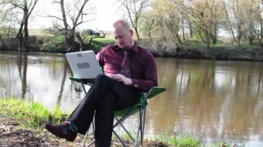 İşadamı oturan ile bir Tablet ve iş için kamp için nehir tarafından zorlanır