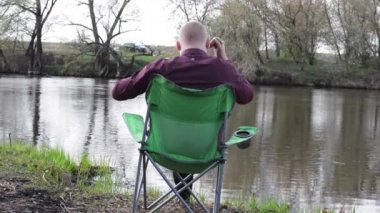 Geri ile bir Tablet tarafından oturan işadamı ve iş için kamp için nehir tarafından zorlanır