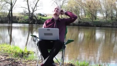 İşadamı oturan ile bir Tablet ve iş için kamp için nehir tarafından zorlanır