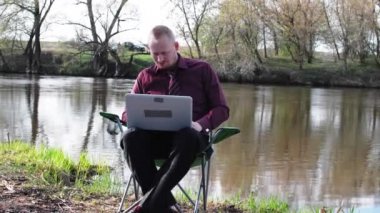 İşadamı oturan ile bir Tablet ve iş için kamp için nehir tarafından zorlanır