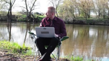 İşadamı oturan ile bir Tablet ve iş için kamp için nehir tarafından zorlanır