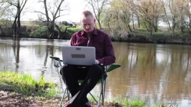 İşadamı oturan ile bir Tablet ve iş için kamp için nehir tarafından zorlanır