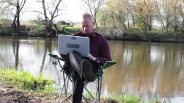 İşadamı oturan ile bir Tablet ve iş için kamp için nehir tarafından zorlanır