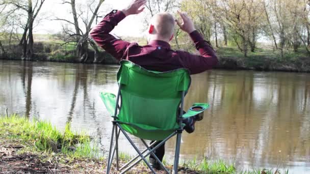 Homme d'affaires assis à l'arrière avec une tablette et est forcé de travailler pour le camping par la rivière — Video