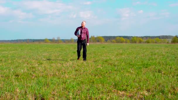 Uomo d'affari stanco che cammina sul campo con il computer portatile — Video Stock