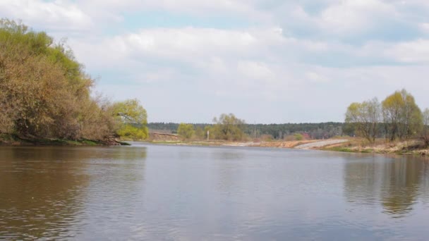 Flujos del río a principios de primavera. las nubes en lo alto de la cabeza. Pescadores atrapan peces, la gente viene a hacer picnics — Vídeo de stock