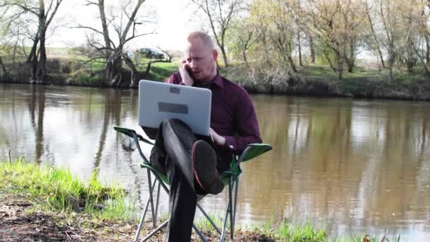 Businessman Sitting With a Tablet,speak Phone, and is Forced to Work For Camping by the River — Stock Video