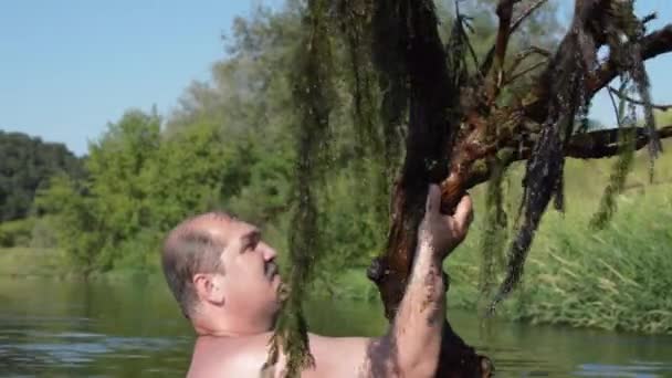 Человек купается в реке с деревом — стоковое видео