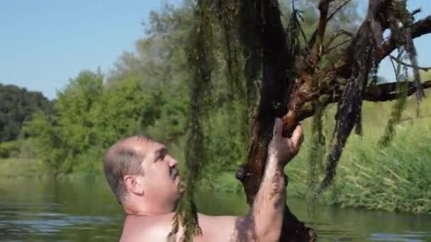 El hombre se baña en el río con un árbol — Vídeo de stock