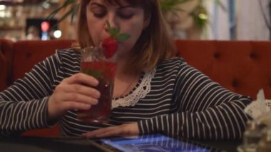 Bir Cafe oturan genç kadın: bilgi Online arıyorsunuz, telefonda konuşurken bir plaka üzerinde Çilekli kokteyl içme