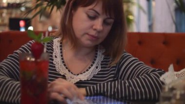 Bir Cafe oturan genç kadın: bilgi Online arıyorsunuz, telefonda konuşurken bir plaka üzerinde Çilekli kokteyl içme