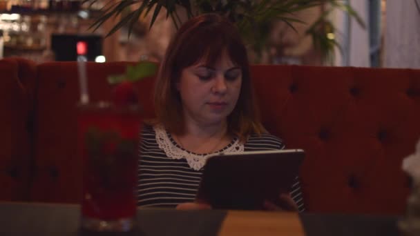 カフェに座っている若い女性: オンライン情報を見て、電話で話して、板上いちごのカクテルを飲む — ストック動画