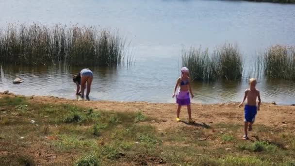 Los turistas lavan la ropa en el río después de la campaña. Niños caminando por la orilla — Vídeos de Stock