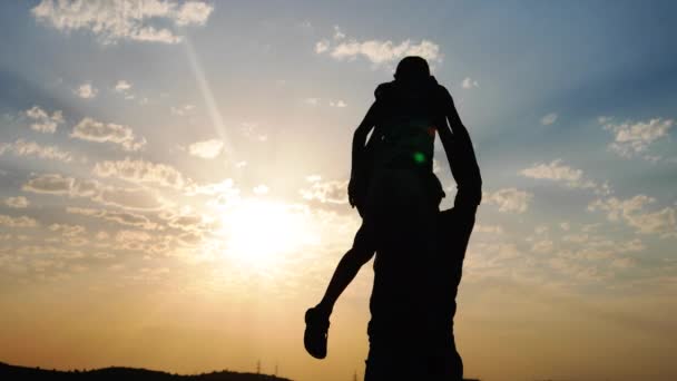 Siluetas contra la puesta de sol papá lanza chico — Vídeo de stock