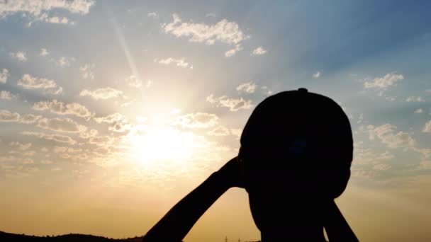 Silhouette contro il sole tramonto ragazzo guarda in il distanza — Video Stock