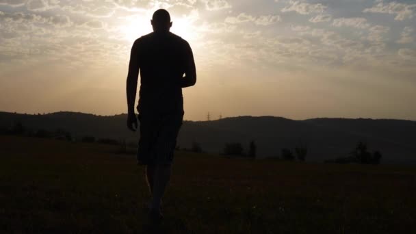 Silhouet van een Man gaat in de bergen naar de zon — Stockvideo