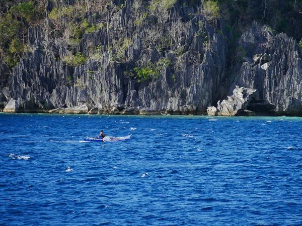 Palawan, Coron, Filipinler 'de bir teknede mavi mayo giymiş sırt çantalı bir adam.