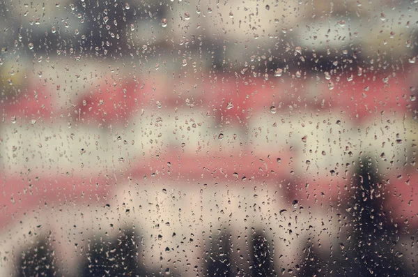 Uitzicht op de stad door een raam met regen druppels — Stockfoto