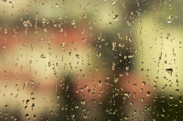 Uitzicht op de stad door een raam met regen druppels — Stockfoto