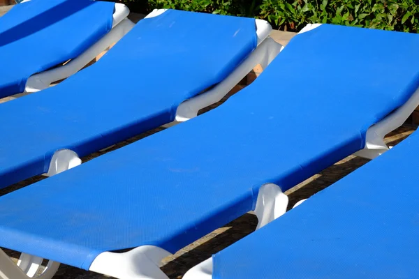 Cadeiras de praia azul e guarda-sol perto da piscina — Fotografia de Stock