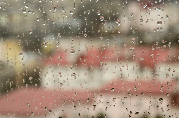 Uitzicht op de stad door een raam met regen druppels — Stockfoto