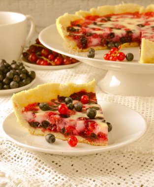 Berry tart, pasta, kek ahududu, bilberries, bluberries, frenk üzümü ve beyaz zemin üzerine krema karıştırın