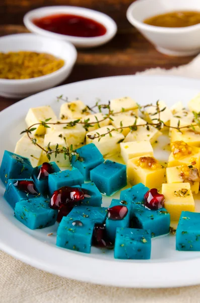 Prato de queijo, Gouda, feta, queijo pesto azul no prato branco com ervas, azeite, romã e molhos de mostarda — Fotografia de Stock