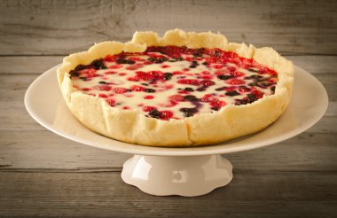 Berry tart, pasta, kek ahududu, bilberries, bluberries, frenk üzümü ve beyaz zemin üzerine krema karıştırın