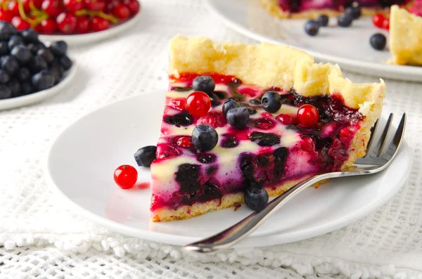 Berry tart, pasta, kek ahududu, bilberries, bluberries, frenk üzümü ve beyaz zemin üzerine krema karıştırın