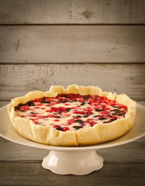 Berry tart, pasta, kek ahududu, bilberries, bluberries, frenk üzümü ve beyaz zemin üzerine krema karıştırın