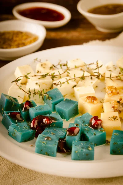 Prato de queijo, Gouda, feta, queijo pesto azul no prato branco com ervas, azeite, romã e molhos de mostarda — Fotografia de Stock