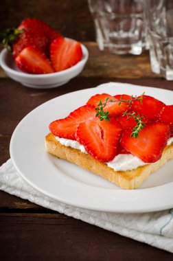 Krem peynir, çilek ve kekik ahşap masa üzerinde kızarmış ekmek