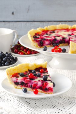 Berry tart, pasta, kek ahududu, bilberries, bluberries, frenk üzümü ve beyaz zemin üzerine krema karıştırın