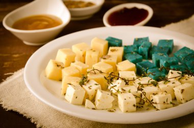 Peynir tabağı, Gouda, beyaz, mavi pesto peynir üzerinde otlar, zeytinyağı, nar ve hardal sos ile plaka beyaz