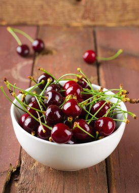 Tahta masadaki kirazlar ve su damlaları.