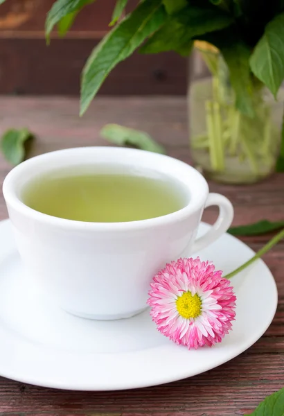 Xícara de chá de ervas com camomilas selvagens, hortelã e flores — Fotografia de Stock