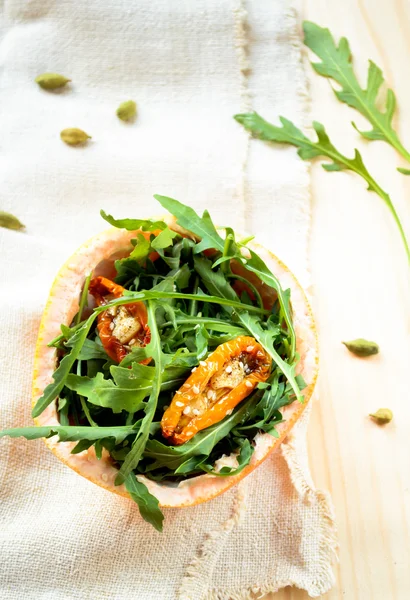 Salada com rúcula, tomates secos ao sol e sésamo em toranja — Fotografia de Stock