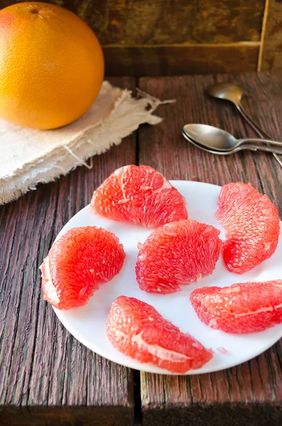 Pamplemousse frais mûr avec des tranches sur une table en bois — Photo