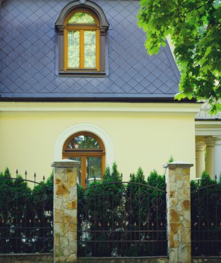 Sarı ev cephe çit ve yeşil ağaçları ile