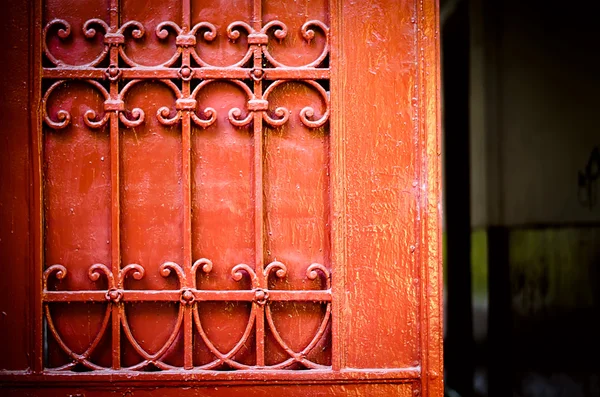 Červené dveře detail s ornamenty z tepaného železa — Stock fotografie