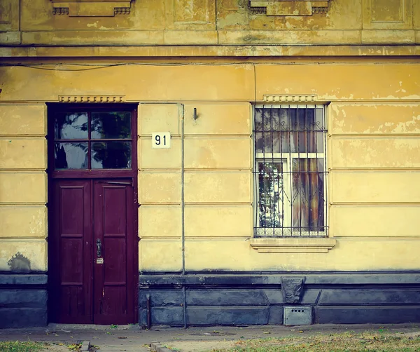 Παλιά πρόσοψη κίτρινο σπίτι με την κόκκινη πόρτα — Φωτογραφία Αρχείου