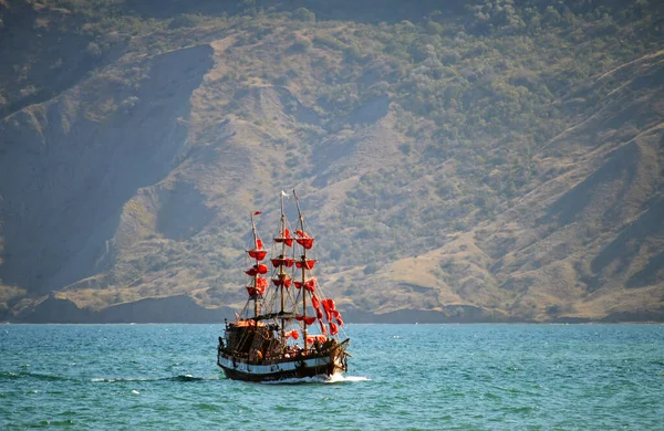 Kırmızı yelkenli bir gemi denizde seyrediyor.