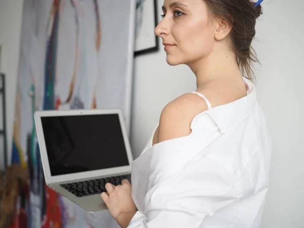 Evden bilgisayarla çalışan genç bir kadın, uzaktan kumanda.