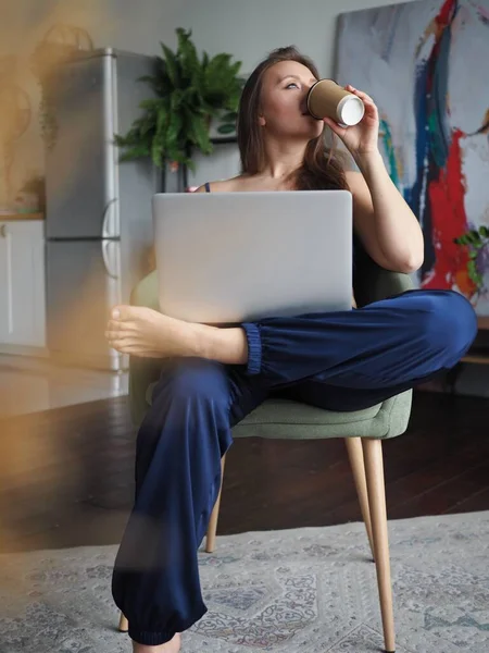 Evden bilgisayarla çalışan genç bir kadın, uzaktan kumanda.