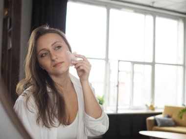 Genç bir kadın yüz masajı yapıyor, vücut masajı yapıyor, anti-selülit masajı yapıyor, kuru fırçayla.