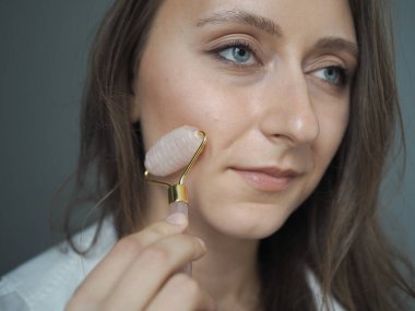 Genç bir kadın yüz masajı yapıyor, vücut masajı yapıyor, anti-selülit masajı yapıyor, kuru fırçayla.