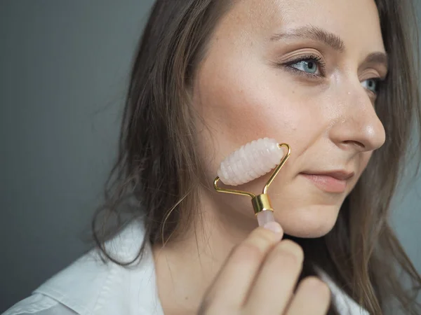 young woman doing face, body massage, anti-cellulite massage with a dry brush