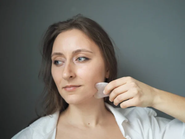 Genç bir kadın yüz masajı yapıyor, vücut masajı yapıyor, anti-selülit masajı yapıyor, kuru fırçayla.