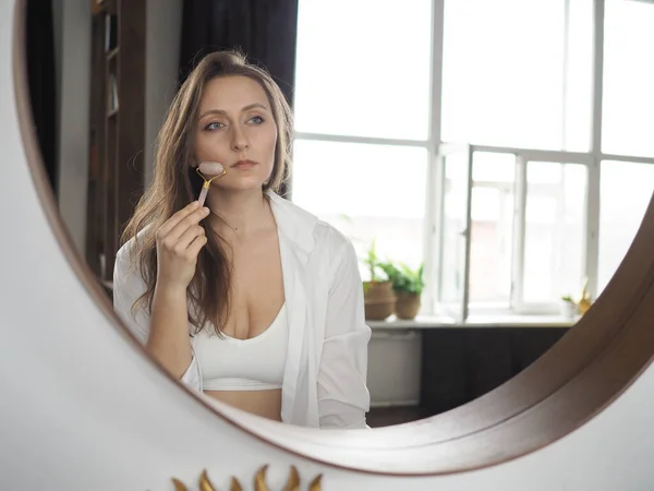 Genç bir kadın yüz masajı yapıyor, vücut masajı yapıyor, anti-selülit masajı yapıyor, kuru fırçayla.