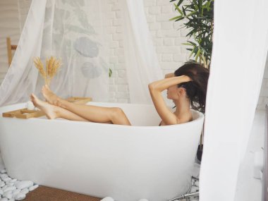 Genç kadın evde banyo yapar, banyo yapar, banyoda yıkanır. Rahatlama